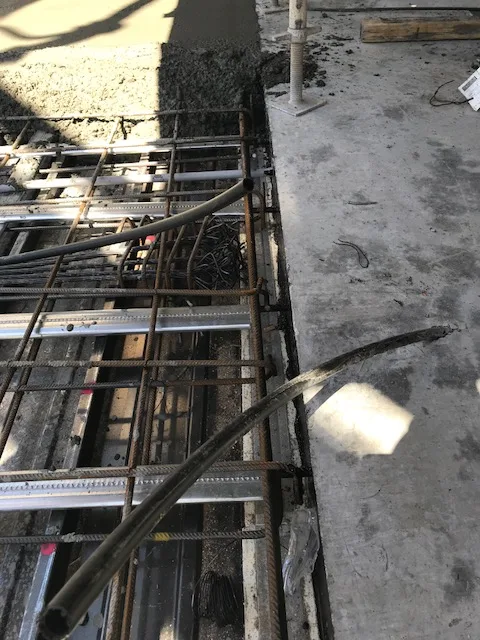 A construction joint in slabs is where the construction of two portions meet. This is an example of a construction joint in a post-tensioned slab with the second pour being freshly poured against the first pour.