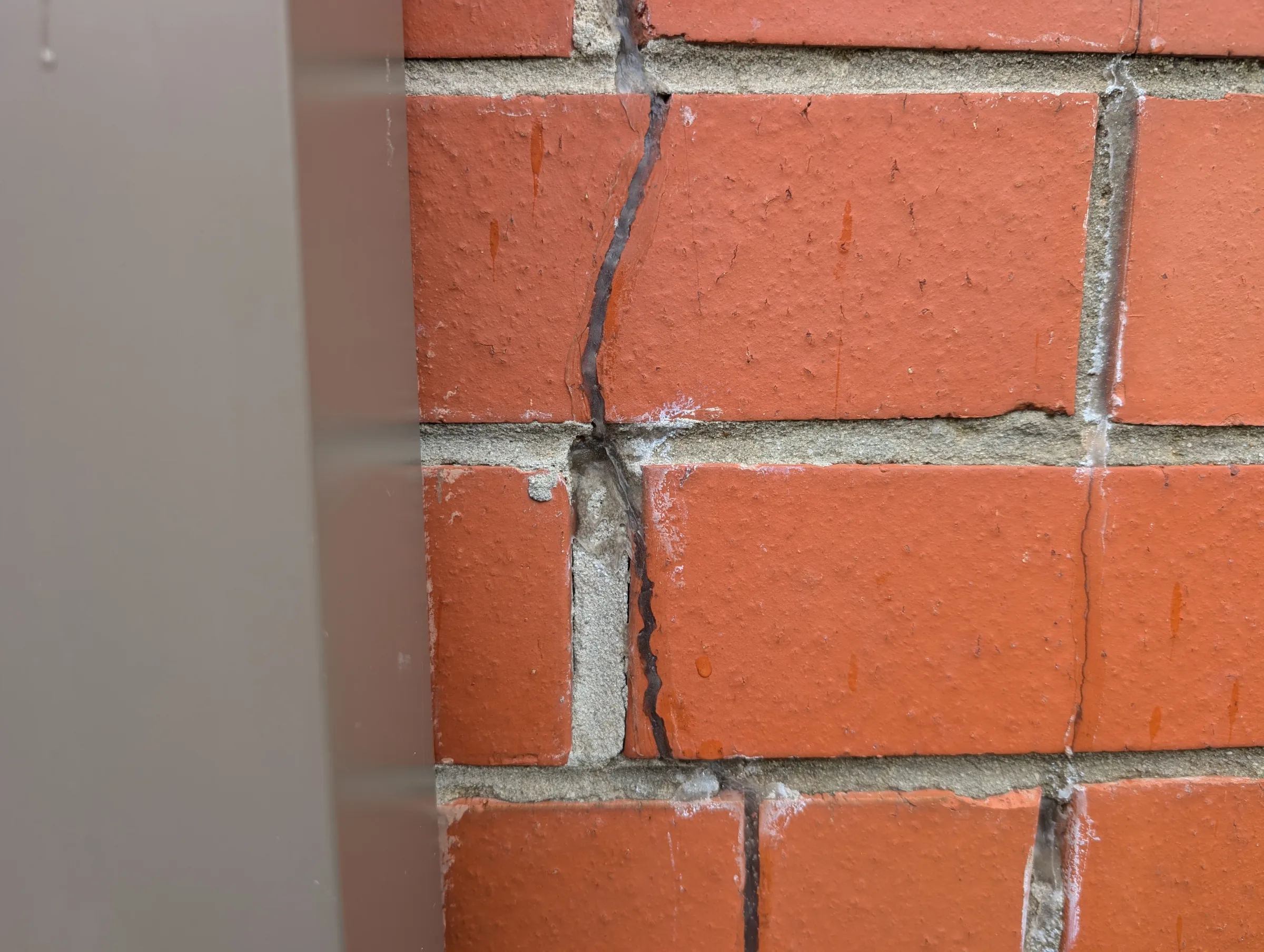 Evidence of previous silicone repairs to existing masonry cracks.